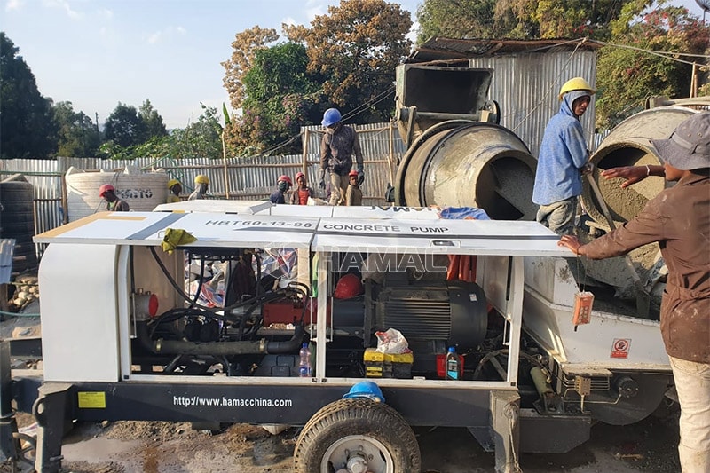 HBT60 electricity concrete pump is delivering the ready mixed concrete poured by two concrete mixers.  